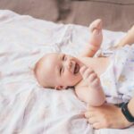 Massaggio neonatale, mani di un genitore sul corpo del bambino